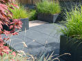 Moderne tuin met grote terrastegels en plantenbakken